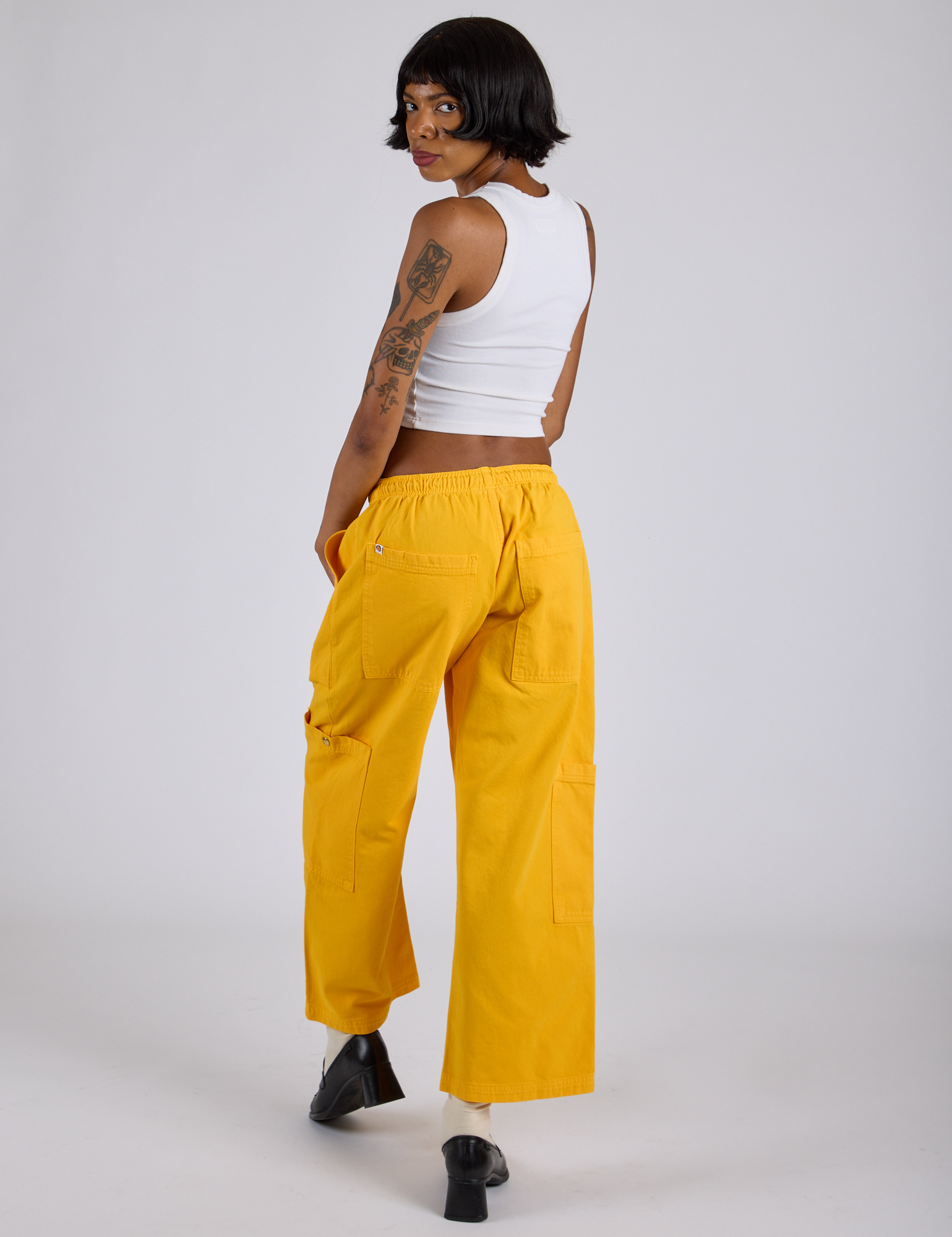 Angled back view of Drop Pocket Cargo Pants in Sunshine Yellow on Kira