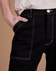 Close up of Quinn's hand in the front pocket of Carpenter Jeans in Black