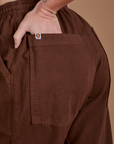 Close up of Alex's hand in the back pocket of Drop Pocket Cargo Pants in Fudgesicle Brown