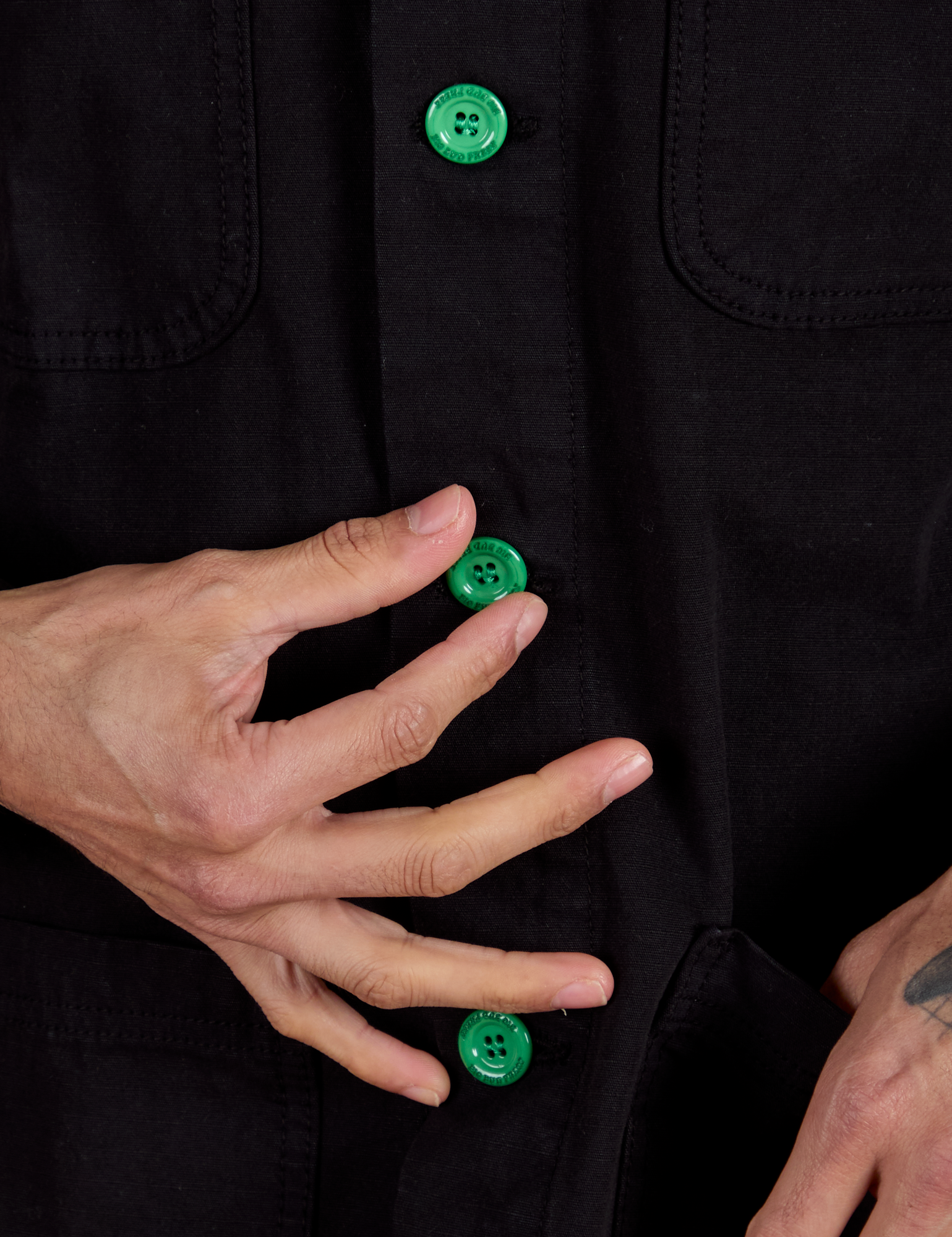 Close up of Ripstop Field Coat in Basic Black with Jesse holding the green button