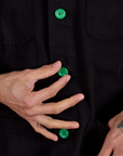 Close up of Ripstop Field Coat in Basic Black with Jesse holding the green button