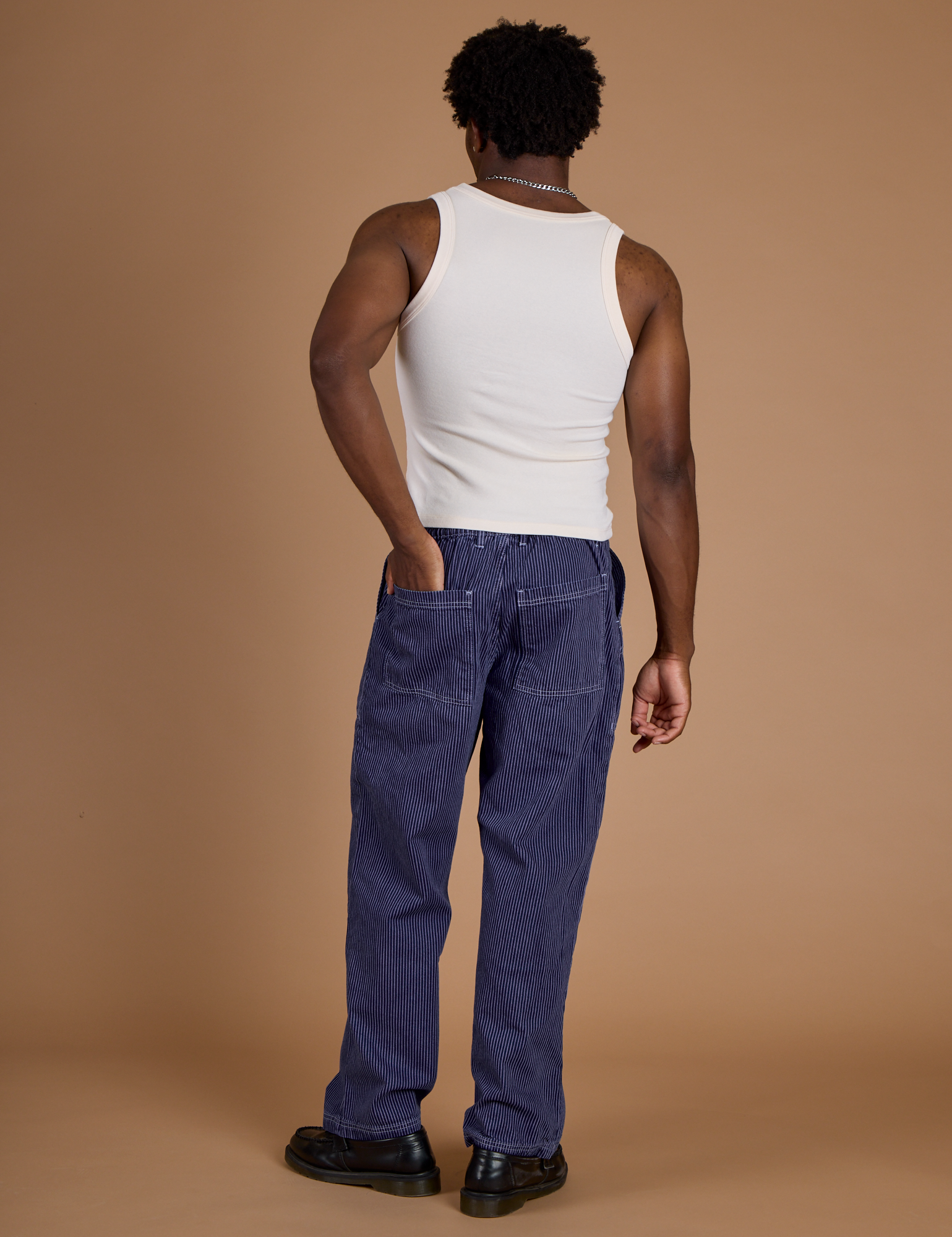Back view of Railroad Denim Work Pants in Faded Grape Overdye and vintage tee off-white Tank Top on Isaac