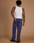 Back view of Railroad Denim Work Pants in Faded Grape Overdye and vintage tee off-white Tank Top on Isaac