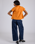 Back view of Pantry Button-Up in Creamsicle Orange and dark wash Denim Drop Pocket Pants