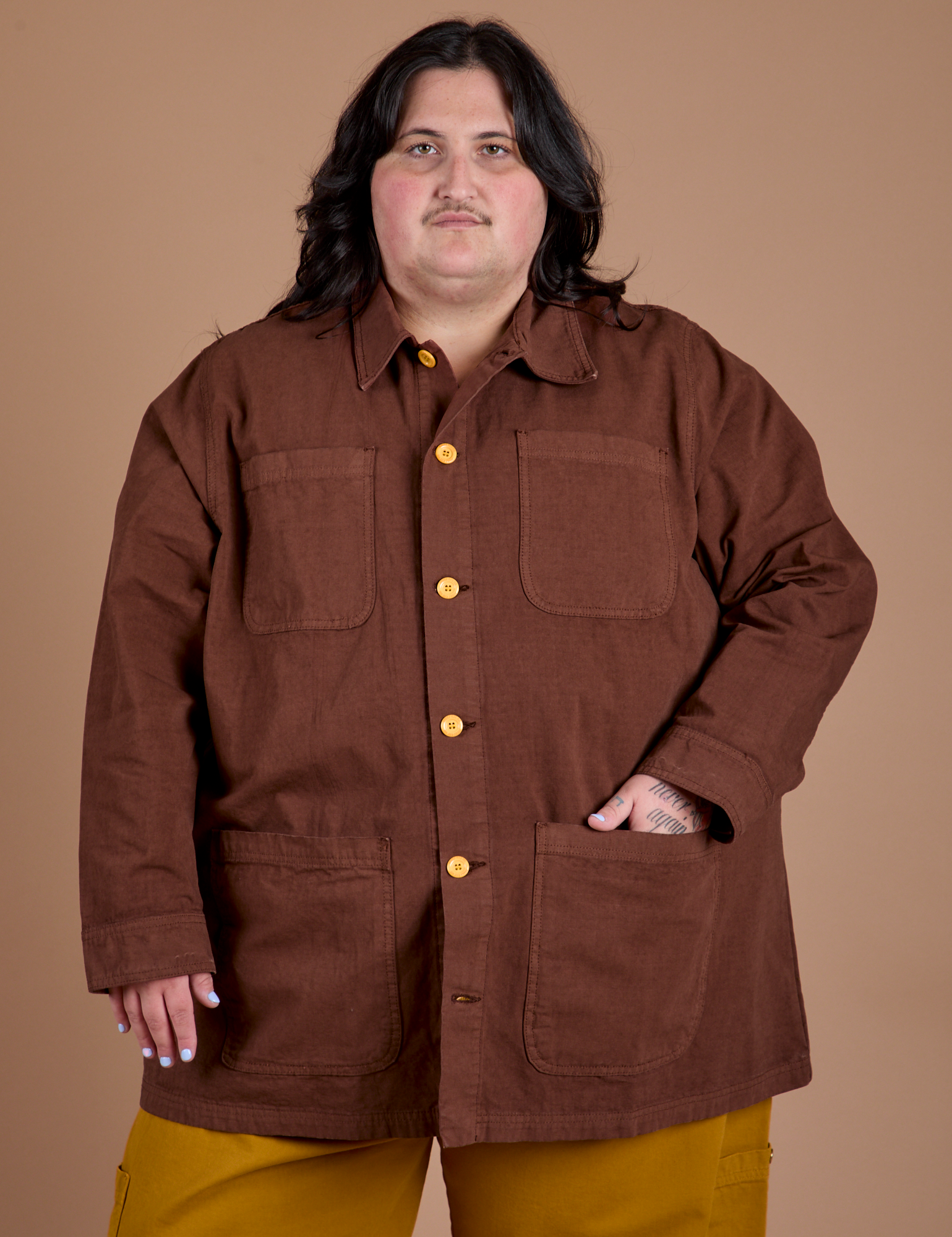 Sam is wearing a buttoned up Ripstop Field Coat in Fudgesicle Brown