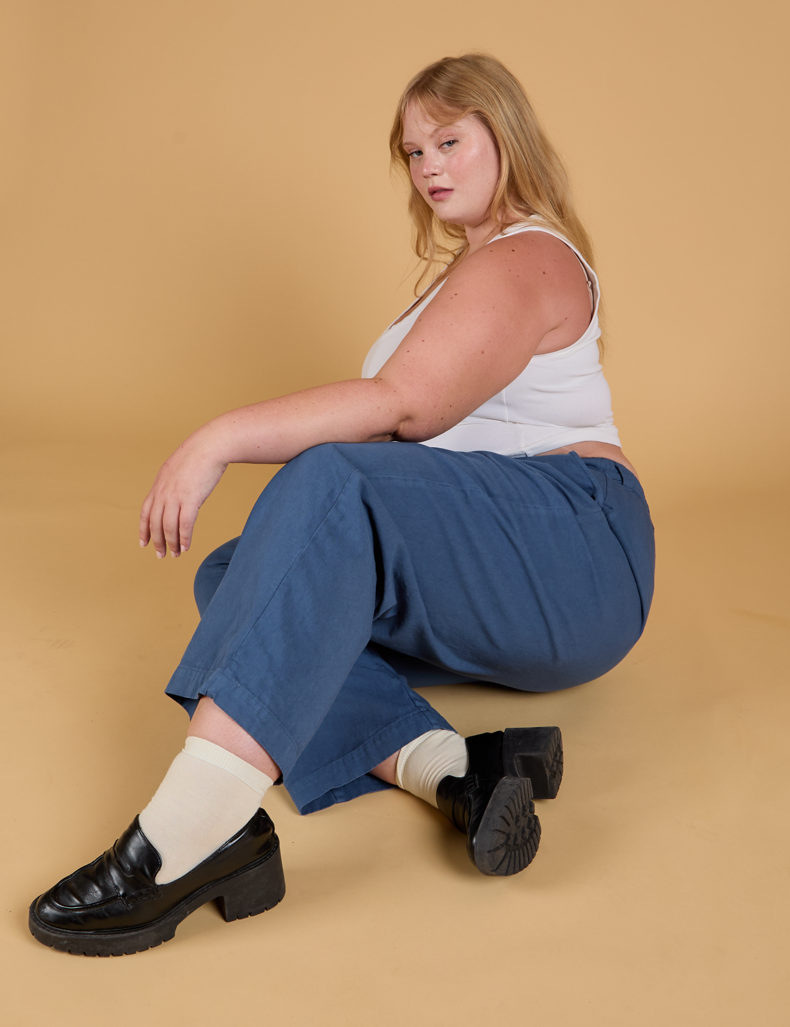 Juliet is sitting on the floor and wearing Baggy Mid-Rise Trousers in French Blue