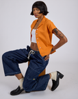 Pantry Button-Up in Creamsicle Orange and dark wash Denim Drop Pocket Pants worn by Kira