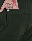 Close up of Sam's hand in the back pocket of Short Sleeve Jumpsuit in Swamp Green 