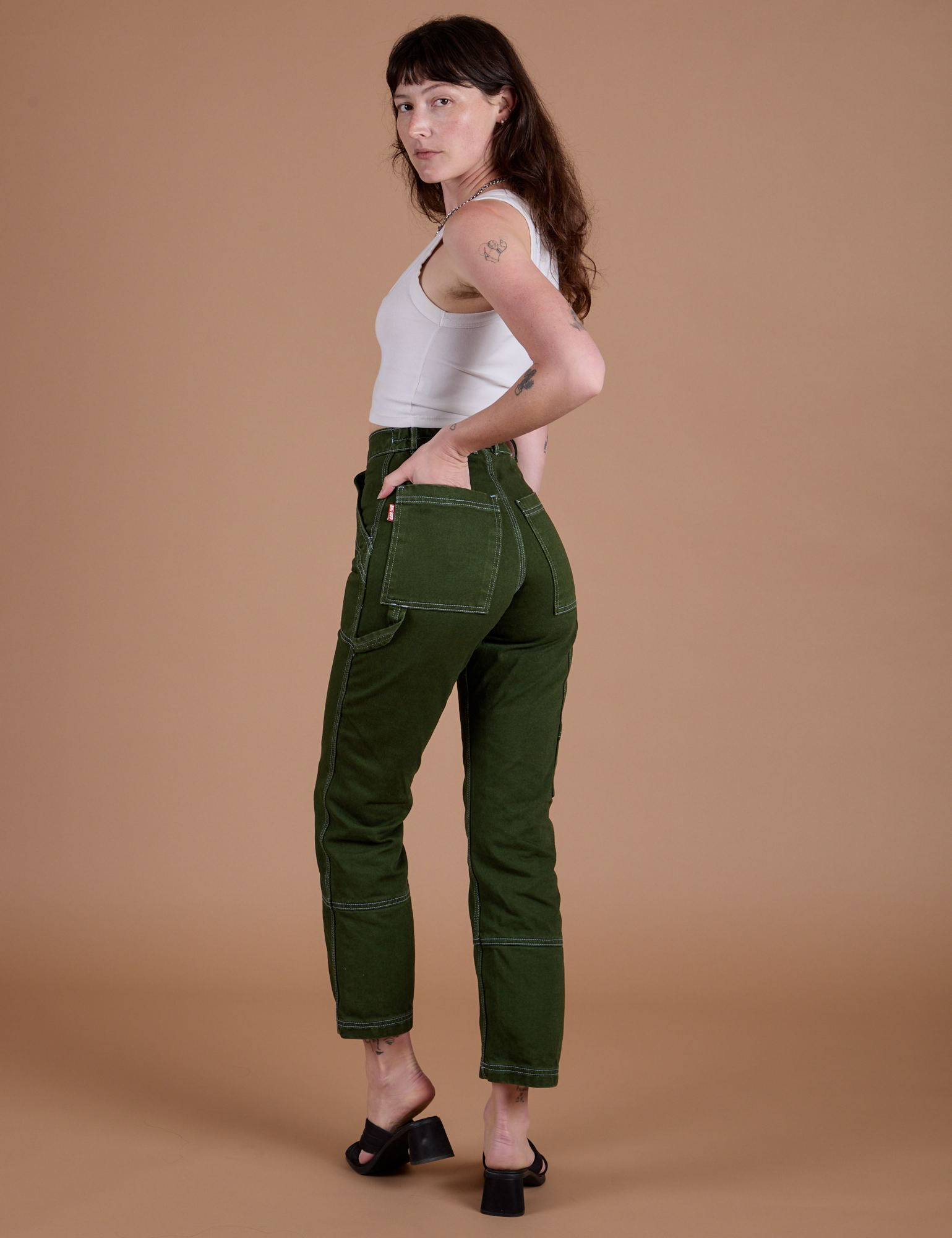 Carpenter Jeans in Evergreen angled back view on Alex