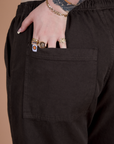 Close up of Sydney's hand in the back pocket of Action Pants in Espresso Brown