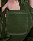 Close up of Alex's hand in the back pocket of Carpenter Jeans in Evergreen