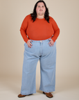 Sam is wearing Long Sleeve Baby Tee in Chili Red and light wash Indigo Wide Leg Trousers