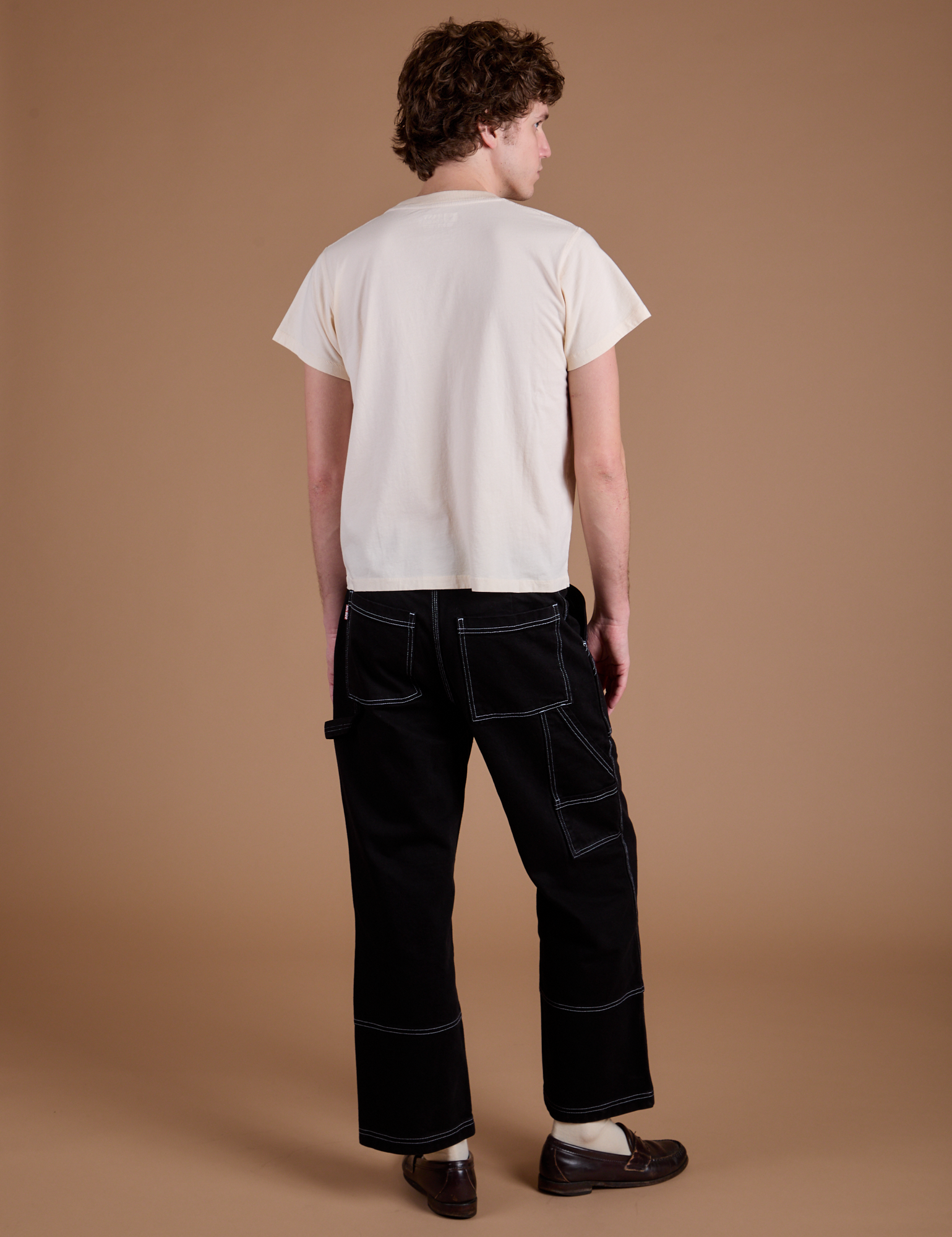 Back view of Carpenter Jeans in Black and the Organic Vintage Tee in Vintage Tee Off-White on Quinn