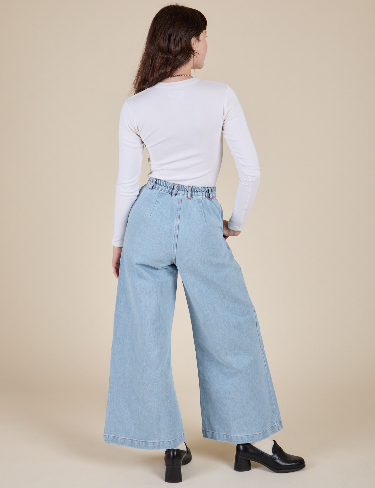 Back view of Long Sleeve Baby Tee in Vintage Tee Off-White and light wash Indigo Wide Leg Trousers