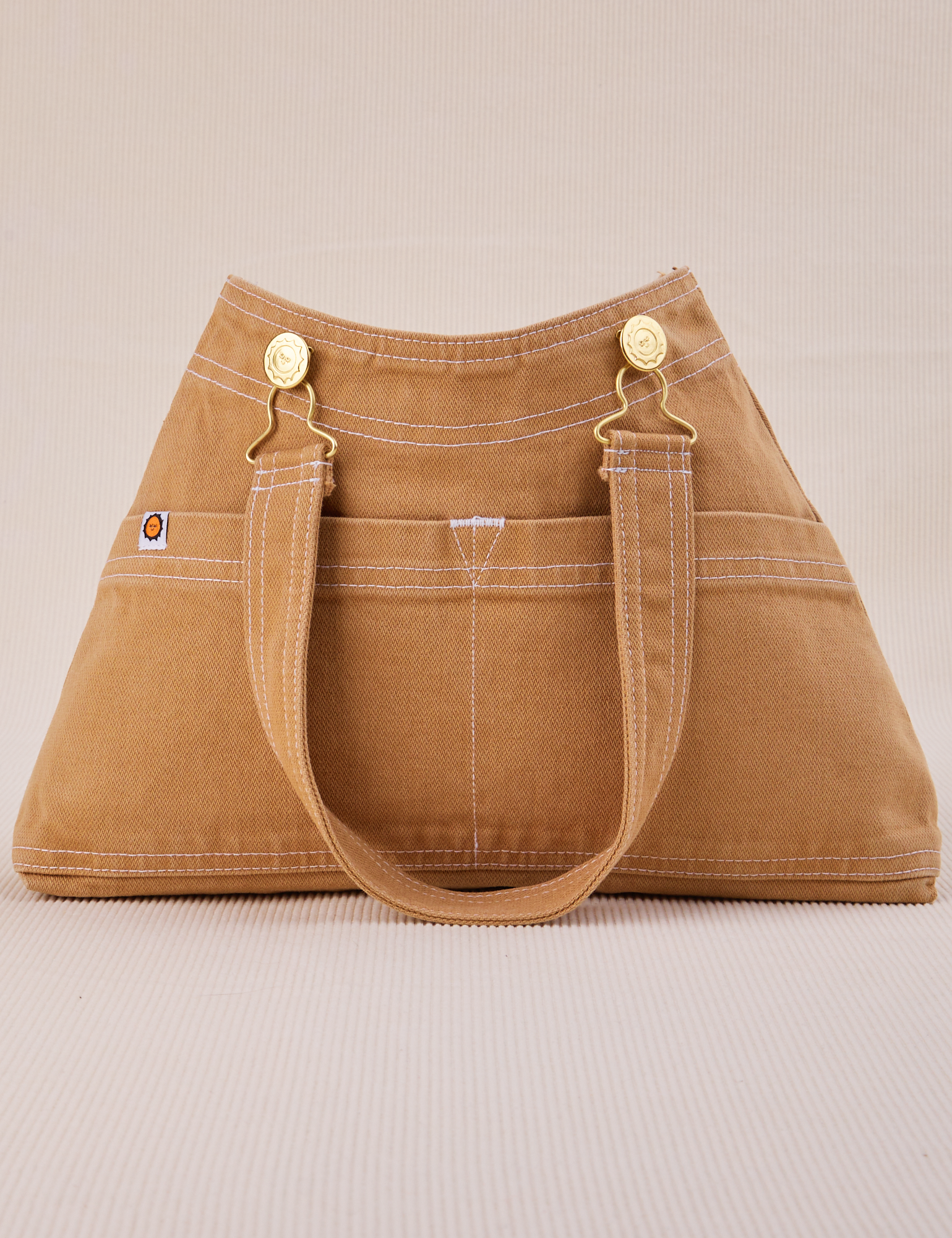 Overall Handbag in Tan with handle strap hanging down front