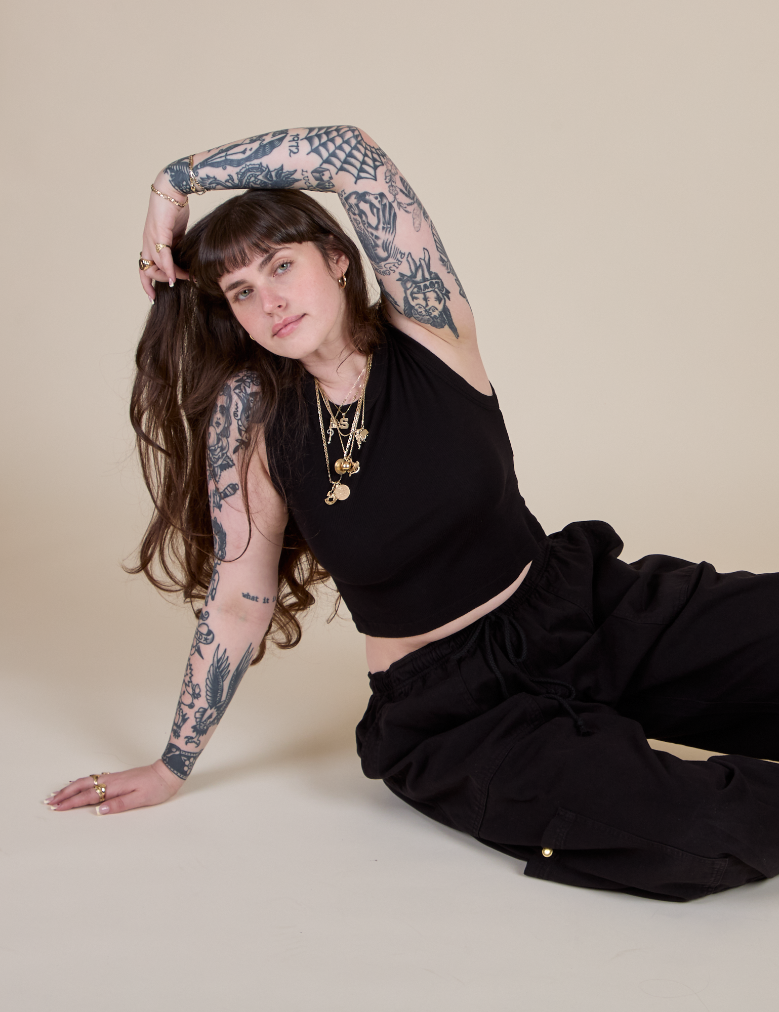 Sydney is sitting on the floor and wearing Muscle Tee in Basic Black and black Drop Pocket Cargo Pants