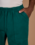 Close up of the Hunter Green Action Pant with Isaac's hand in the front pocket