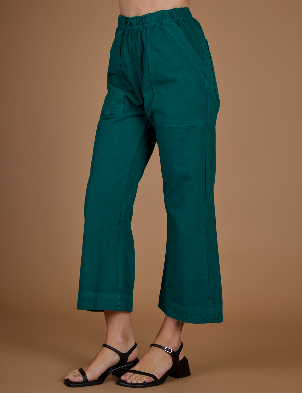 Angled side view of Alex in the the Hunter Green Action Pant