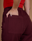 Close up of Alex's hand in the back pocket of the Red Wine Action Pant