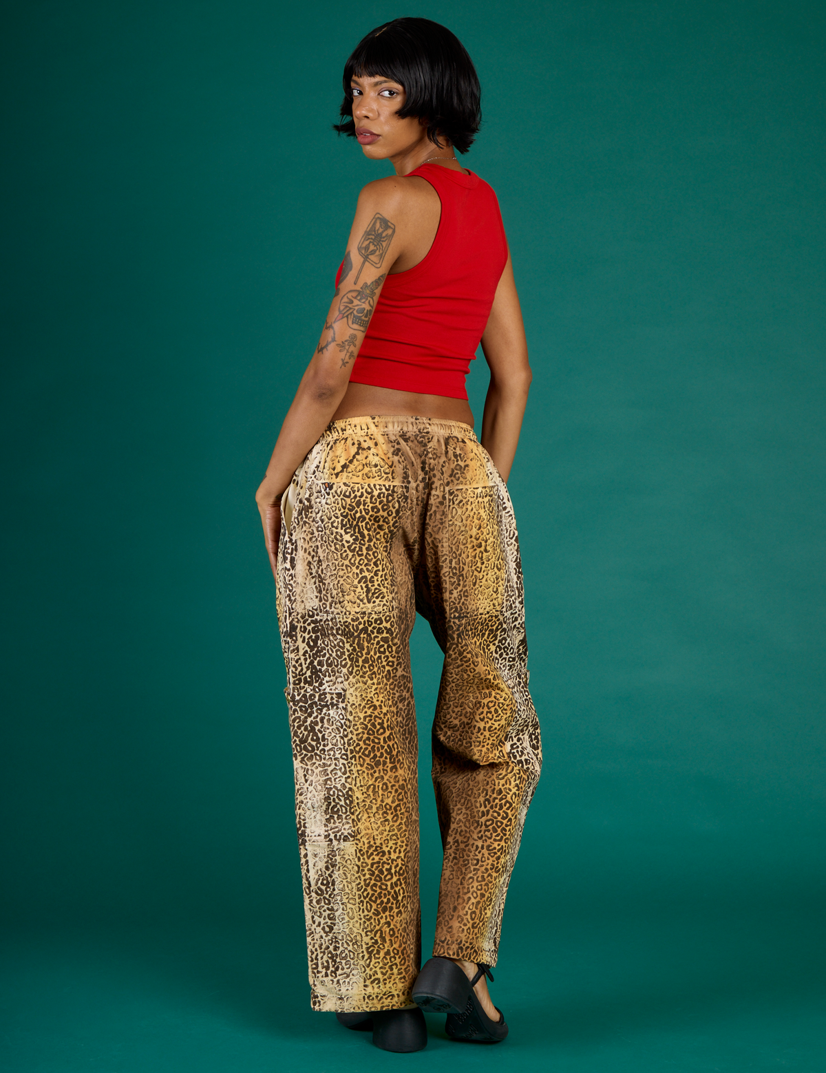 Angled back view of Kira wearing the Leopard Drop Pocket Pant