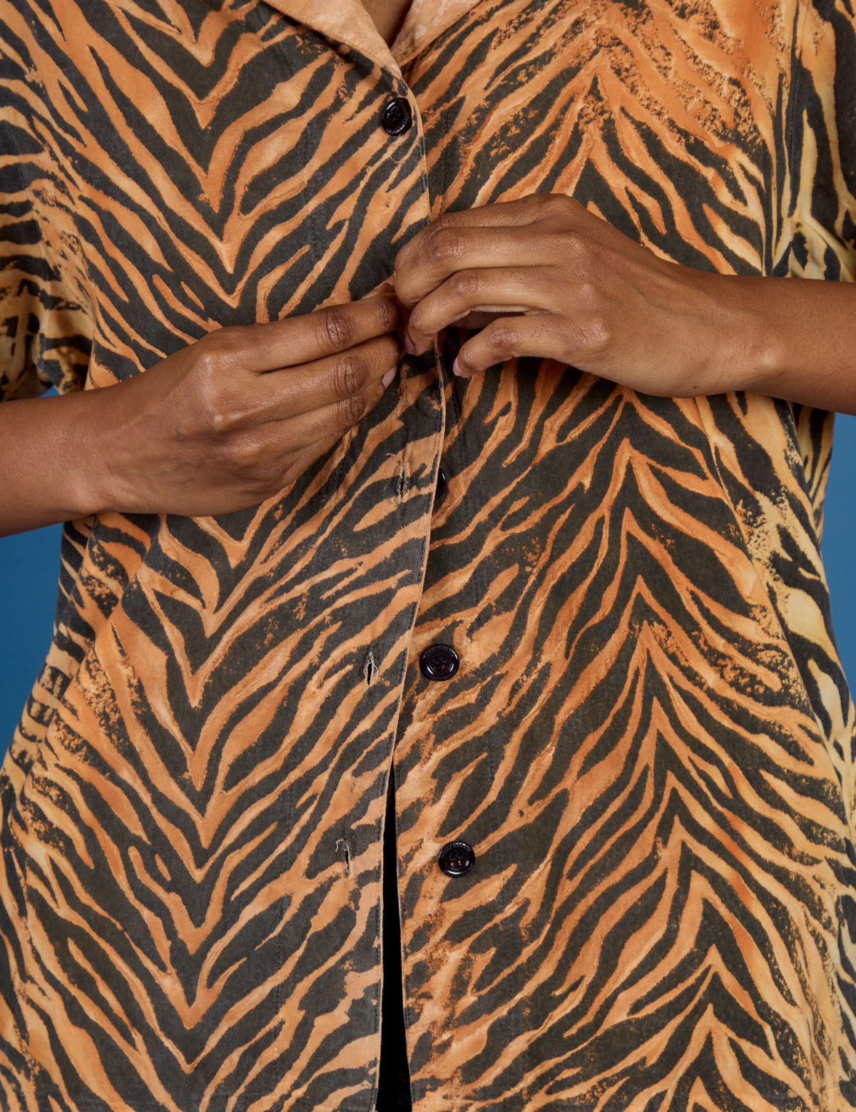 Close up of Kandia buttoning up the Tiger Pantry Button Up