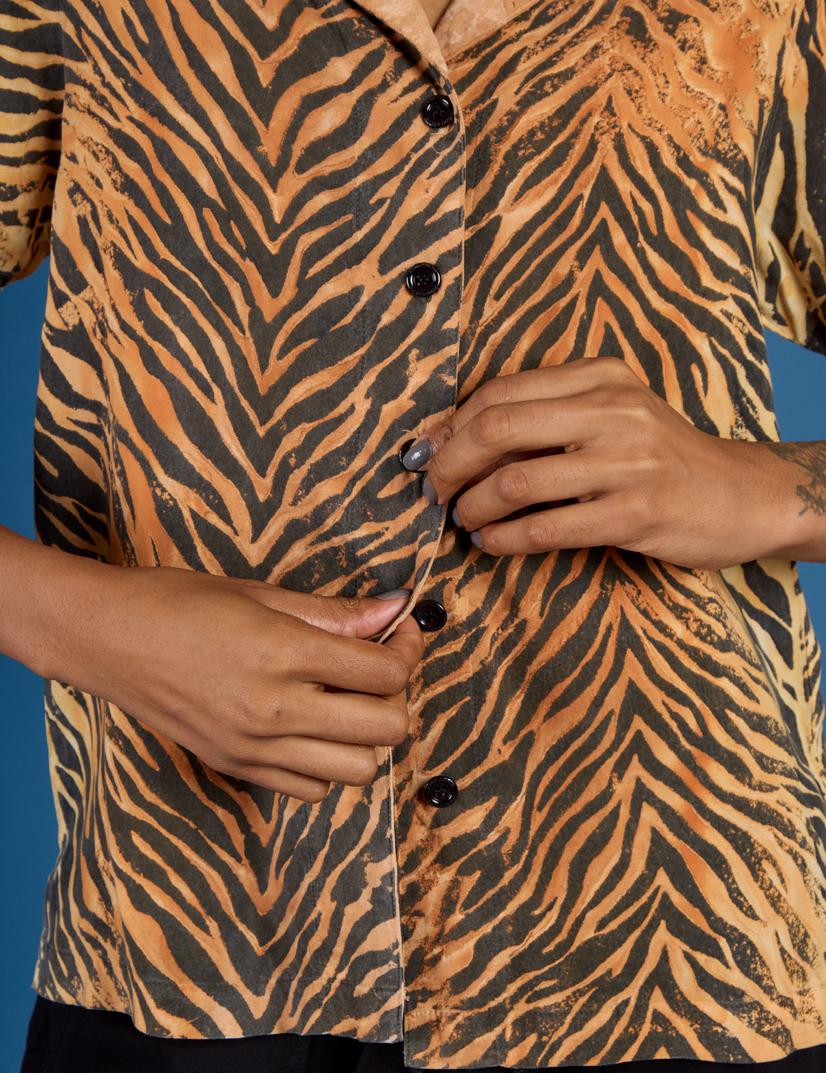 Close up of Kira buttoning up the Tiger Pantry Button Up