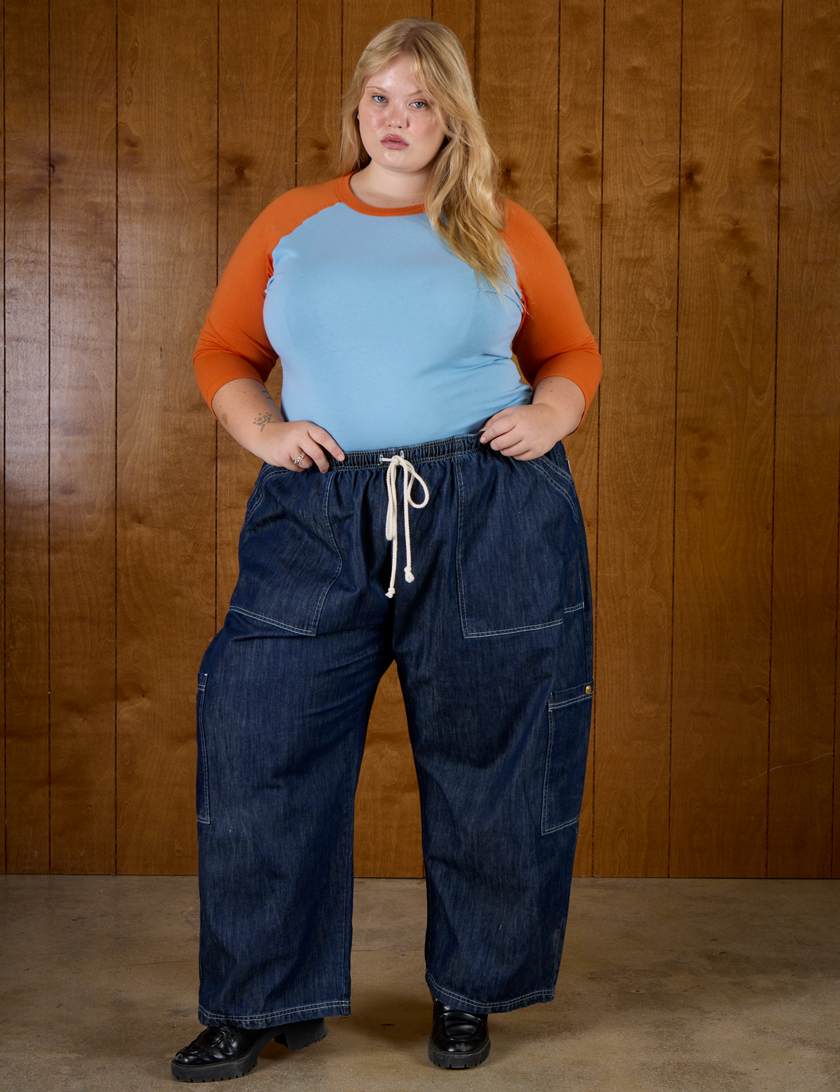 Juliet is wearing the Baby Blue/Orange Colorblock Raglan Tee tucked into the Dark Wash Denim Drop Pocket Pants