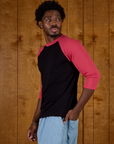 Angled side view of Isaac wearing the Black/Pink Colorblock Raglan Tee