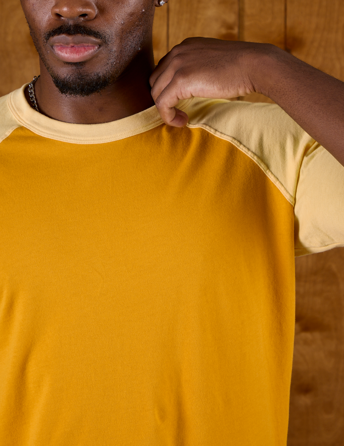 Close up of the neckline of the Mustard Yellow/Butter Raglan Tee on Isaac