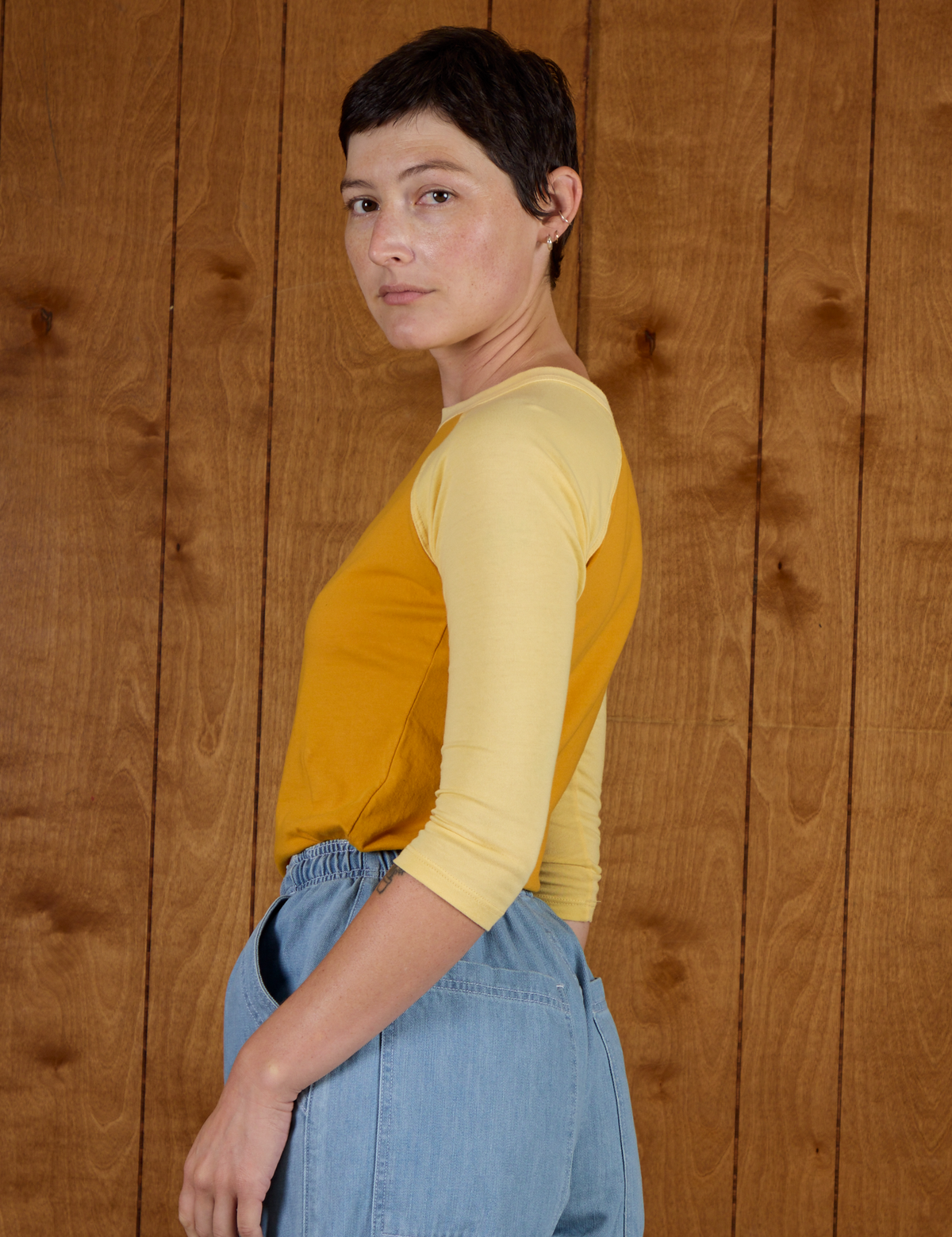 Angled back view of the Mustard Yellow/Butter Raglan Tee on Alex