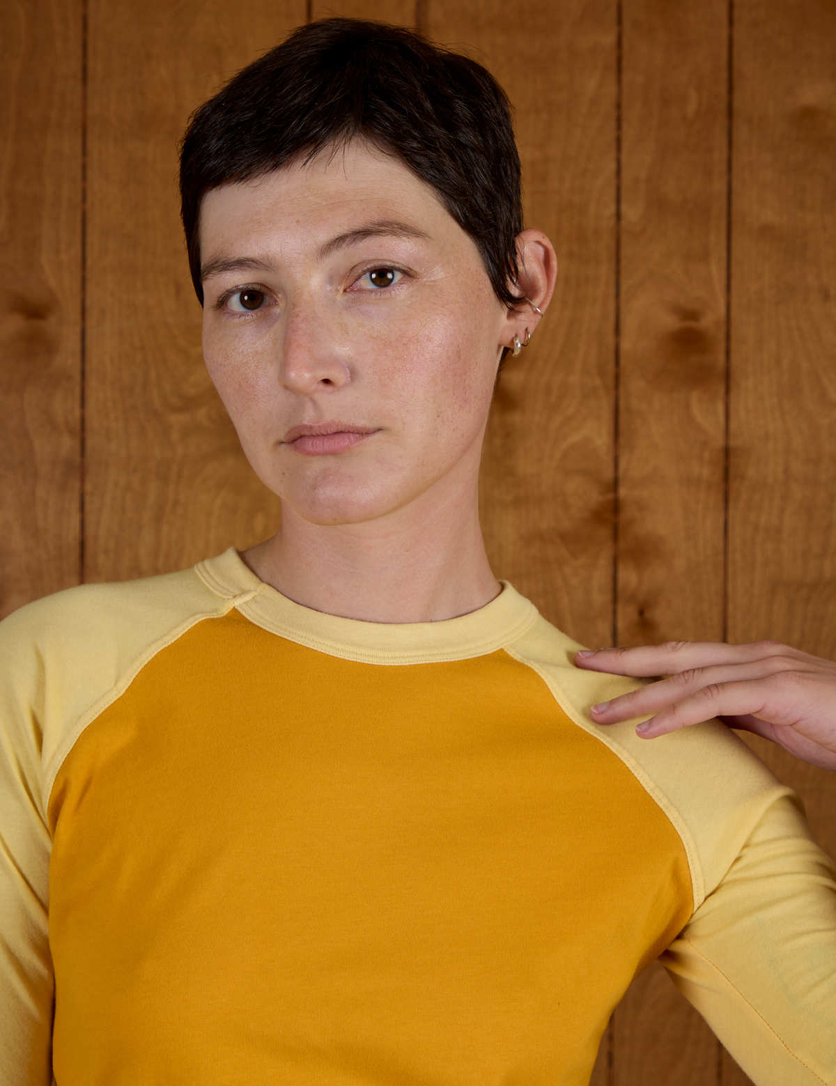 Close up of Alex wearing the Mustard Yellow/Butter Raglan Tee