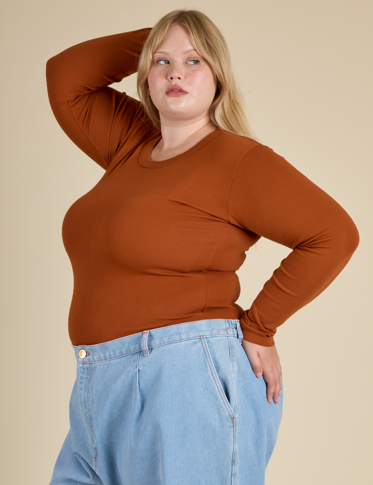 Angled side view of the Burnt Terracotta Long Sleeve Baby Tee on Juliet