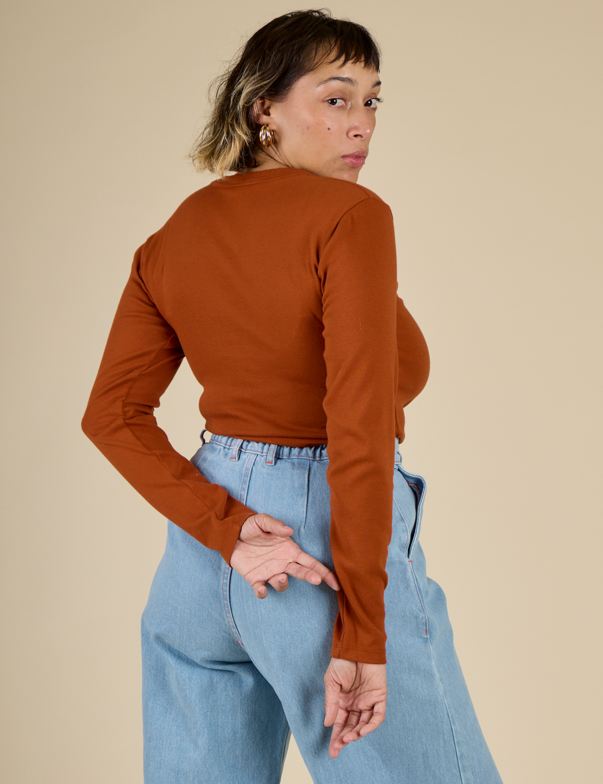 Angled back view of Tiara in the Burnt Terracotta Long Sleeve Baby Tee