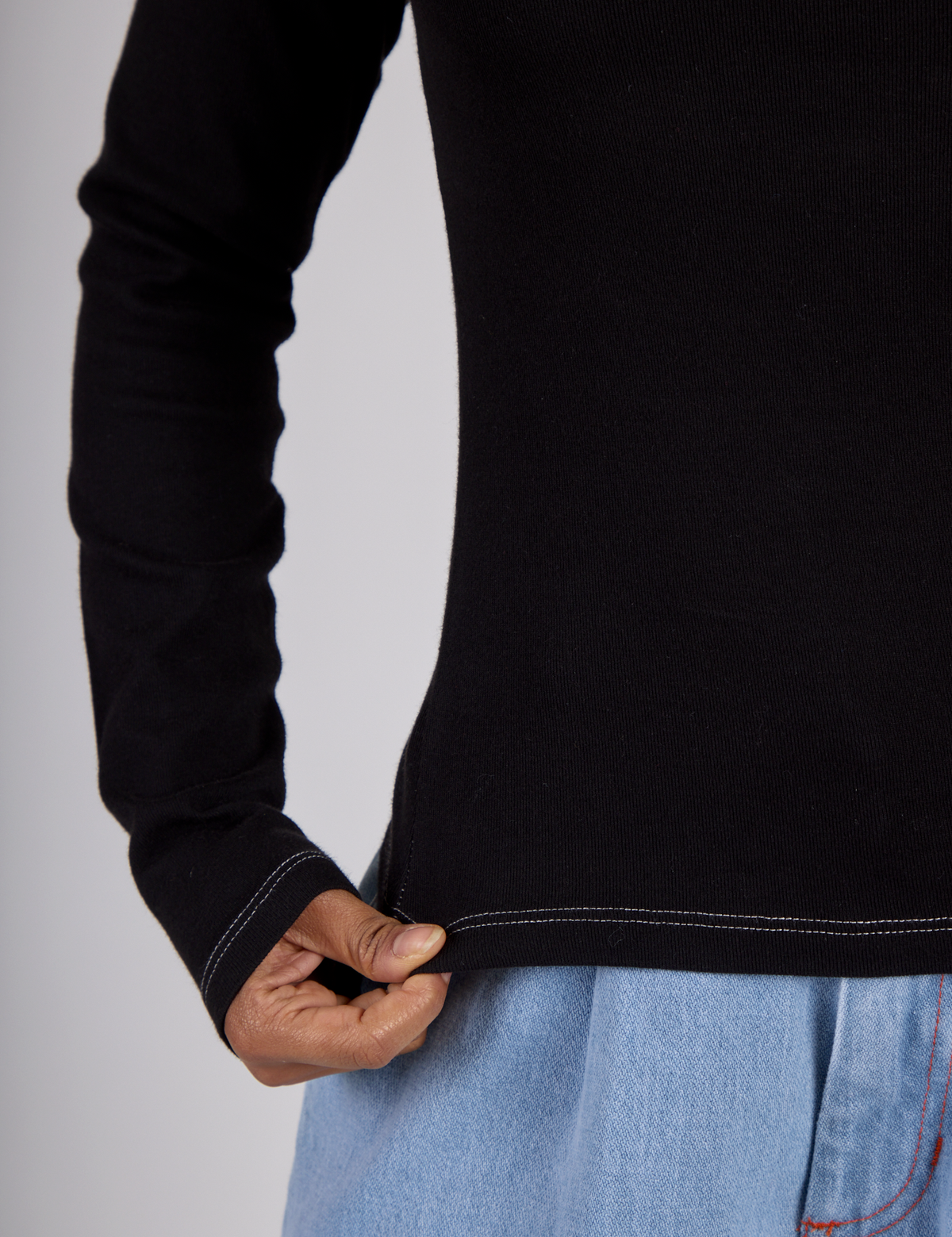 Close up of the Black Porthole Long Sleeve Tee's hem worn by Mika