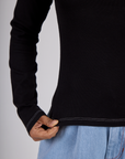 Close up of the Black Porthole Long Sleeve Tee's hem worn by Mika