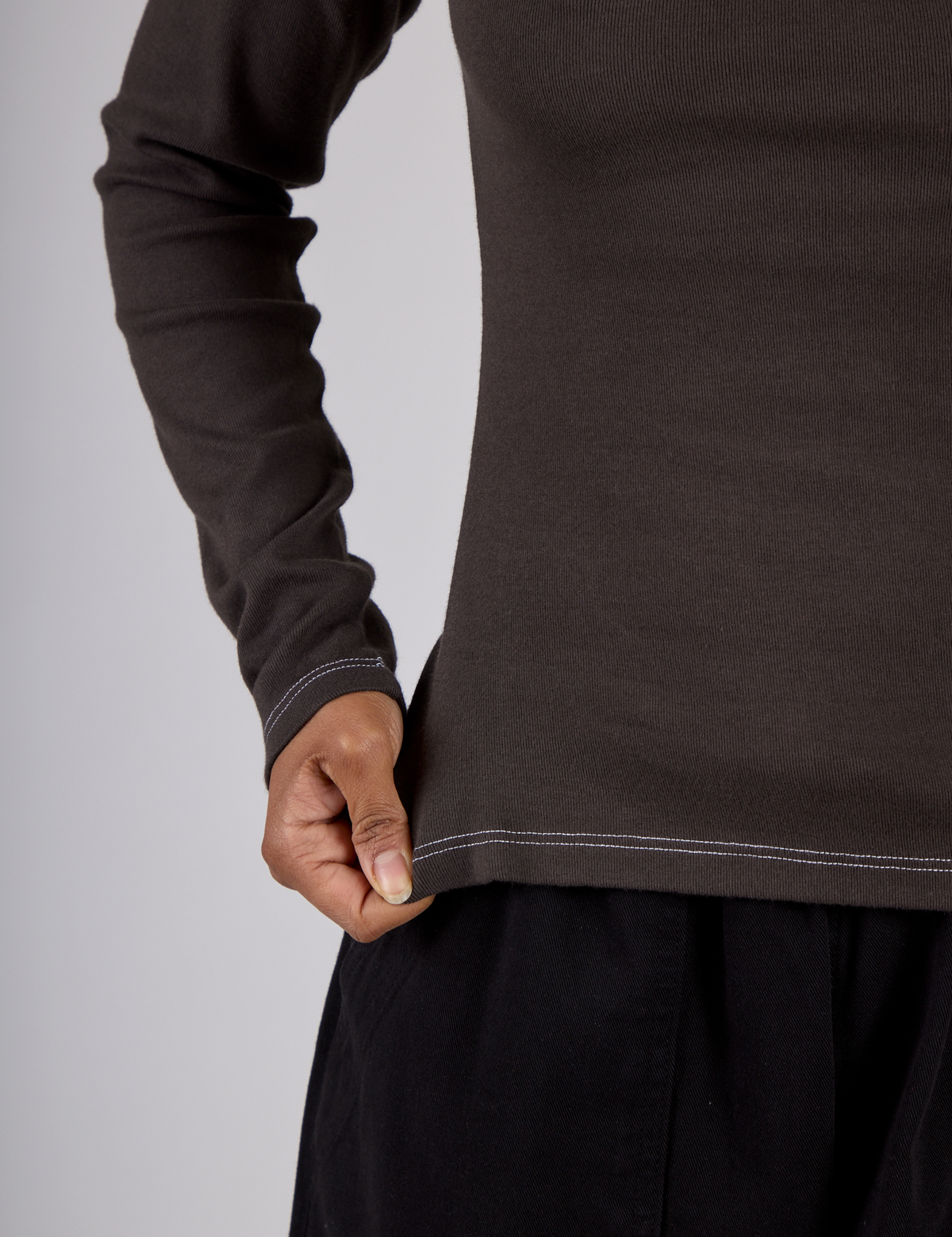 Close up of the Espresso Brown Long Sleeve Porthole Tee's hem worn by Mika