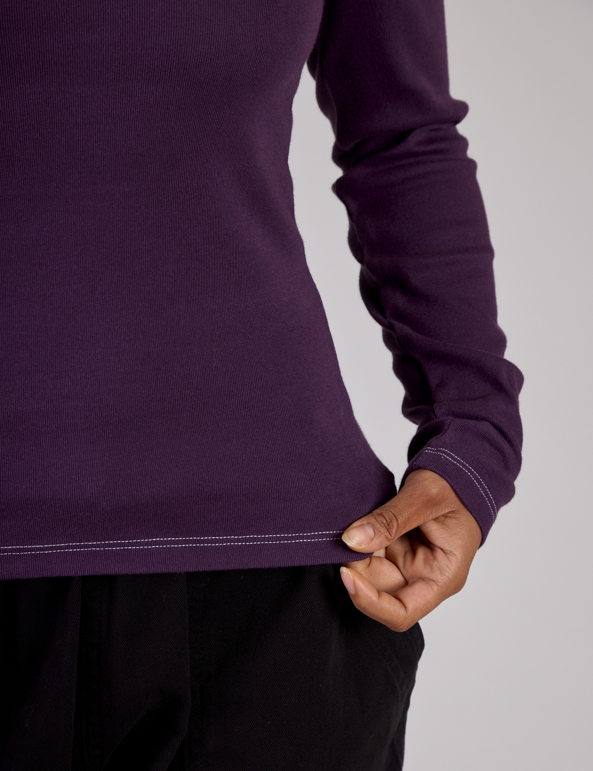 Close up of the Nebula Purple Long Sleeve Porthole Tee's hem worn by Mika