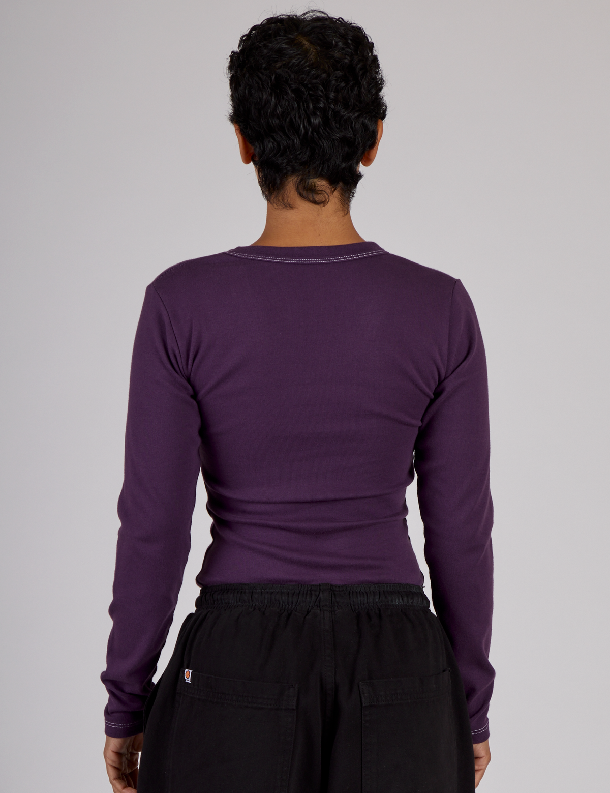 Back view of Mika wearing the Nebula Purple Long Sleeve Porthole Tee