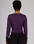 Back view of Mika wearing the Nebula Purple Long Sleeve Porthole Tee