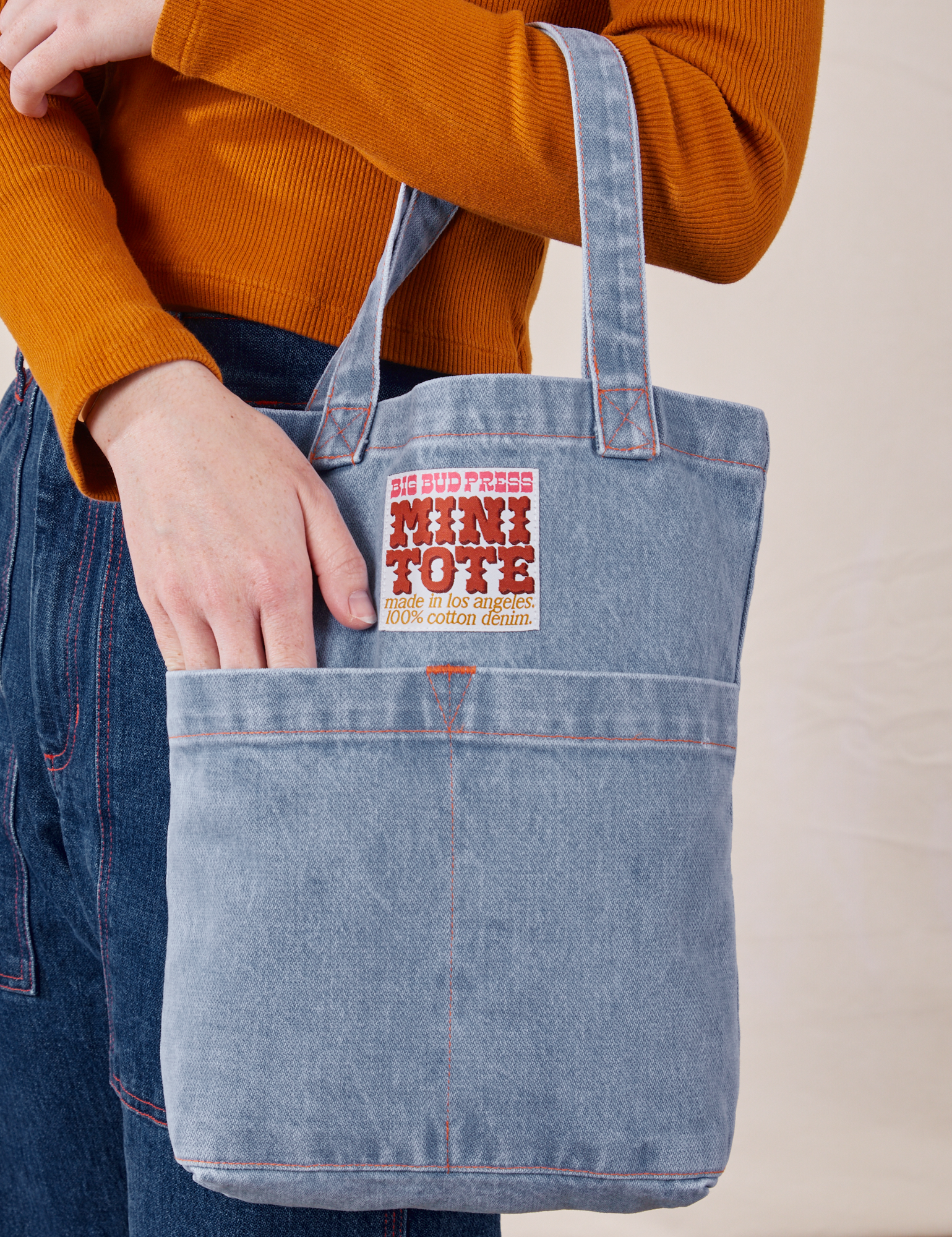 Denim Mini Tote Bag in Light Wash on model's arm with her hand in the front pocket