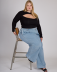 Juliet wearing the Black Porthole Long Sleeve Tee tucked into the Light Wash Wide Leg Denim Trousers