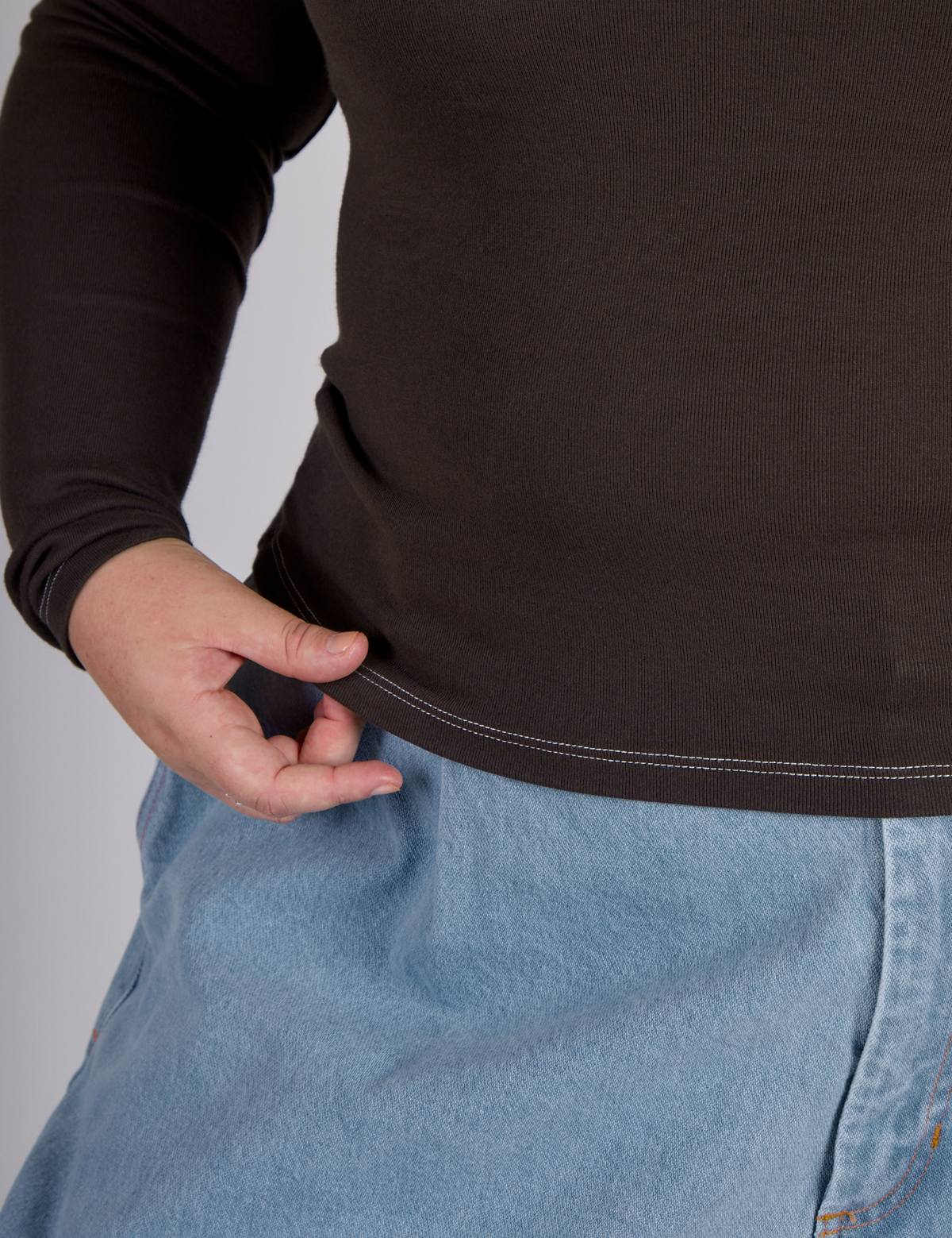 Close up of the Espresso Brown Long Sleeve Porthole Tee's hem worn by Juliet
