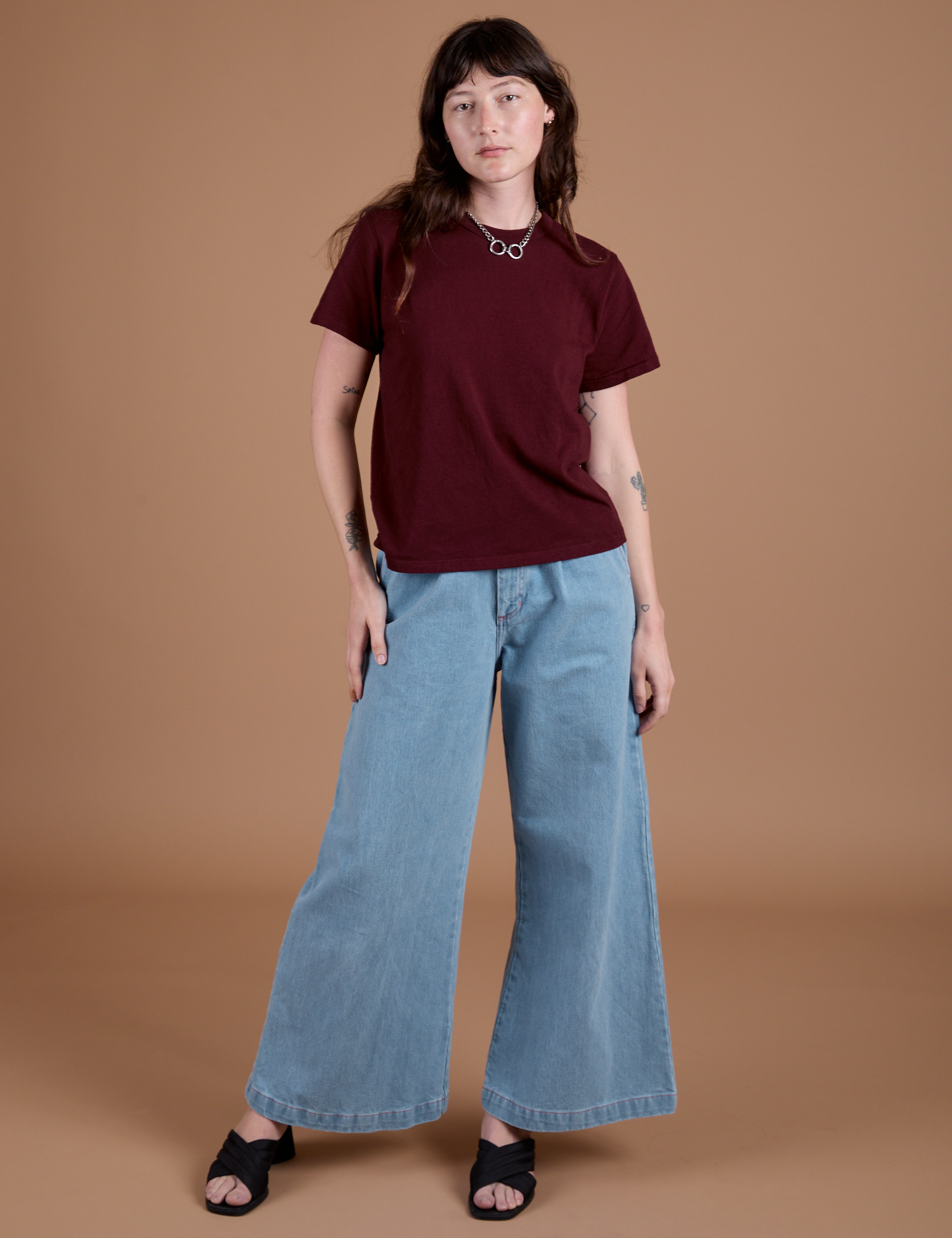 Alex is wearing Burly Tee in Red Wine and light wash Indigo Wide Leg Trousers