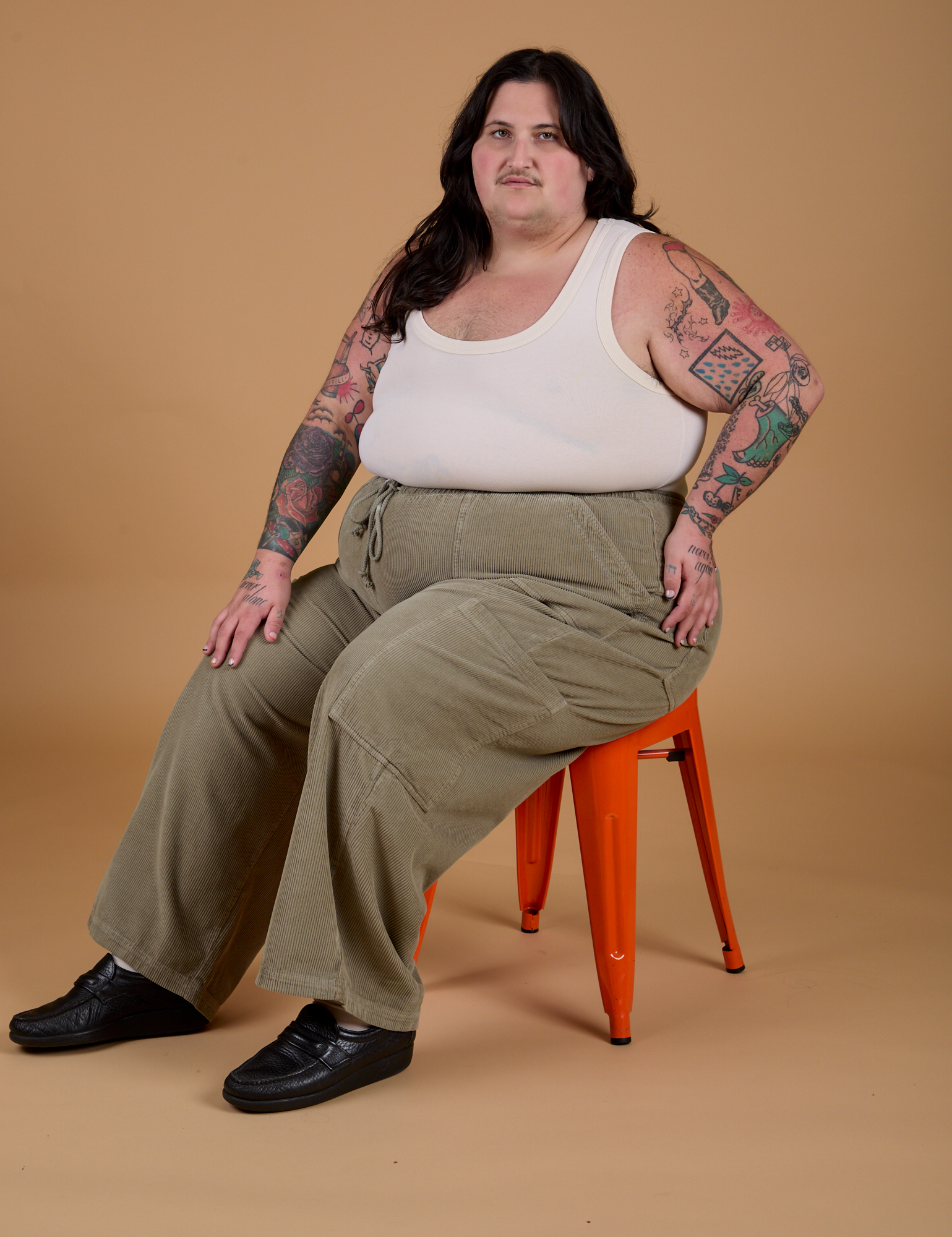 Sam is wearing Corduroy Drop Pocket Cargo Pants in Khaki Grey and Tank Top in Vintage Tee Off-White