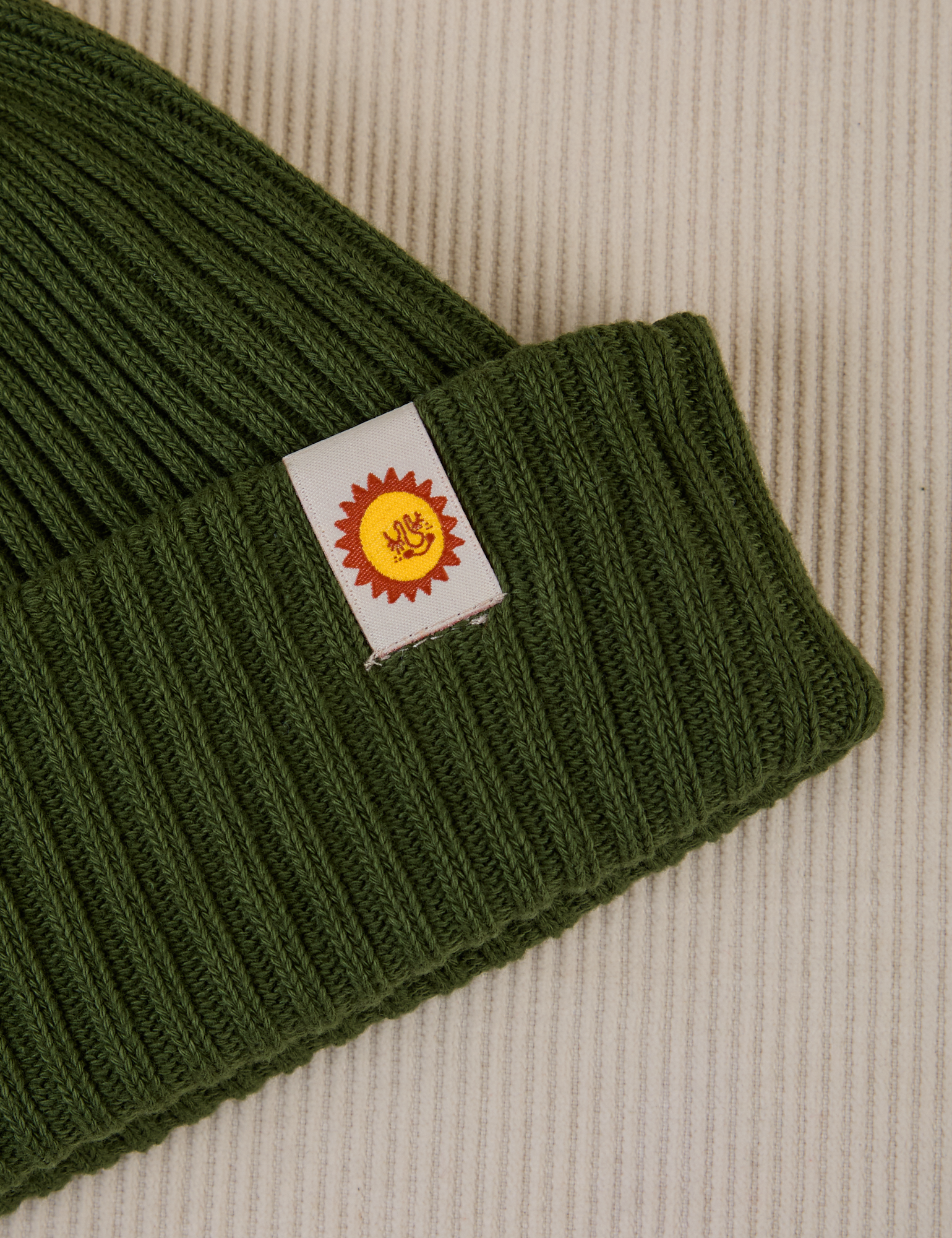 Ribbed Beanie in Evergreen close up of sun baby tag
