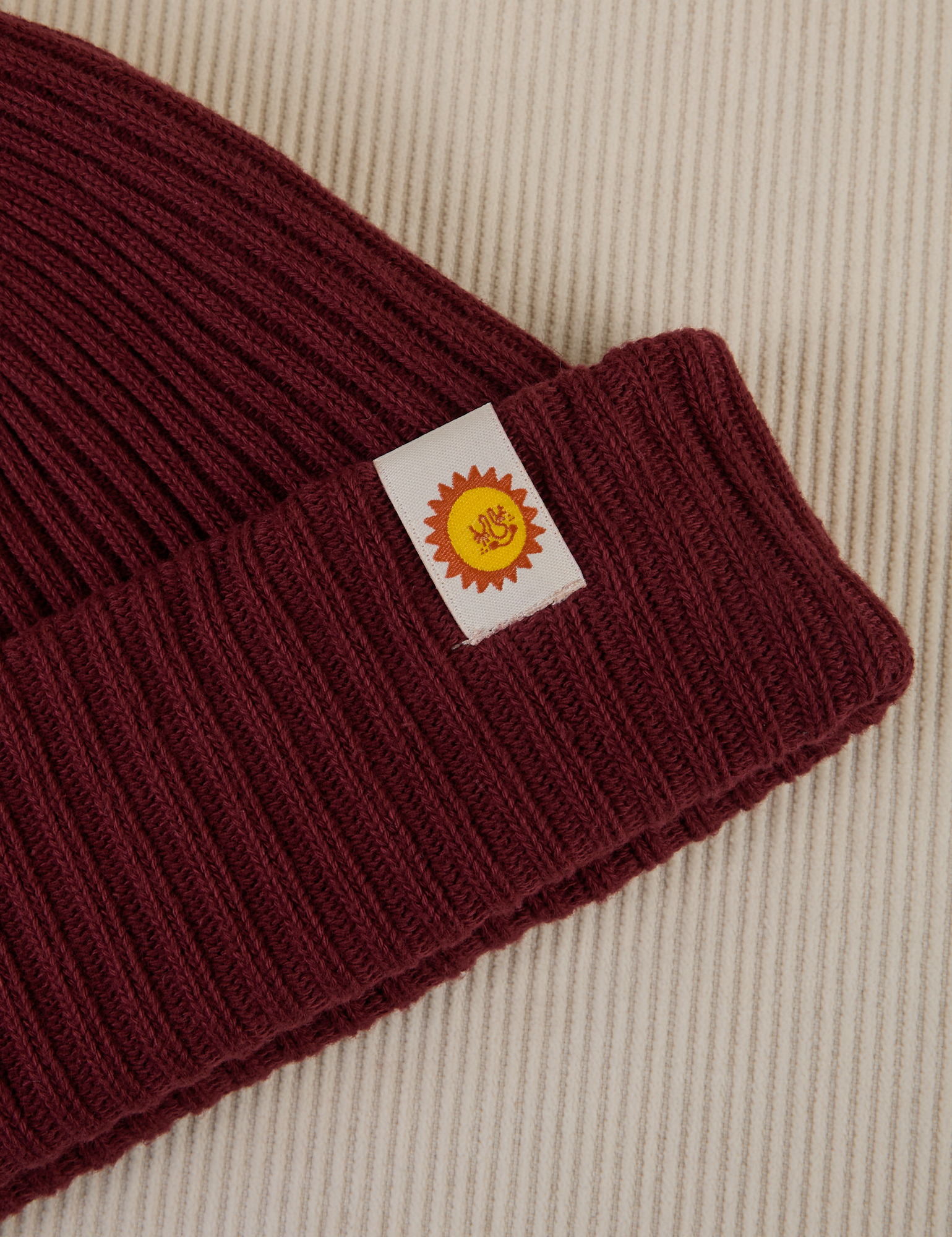 Ribbed Beanie in Red Wine close up of sun baby tag